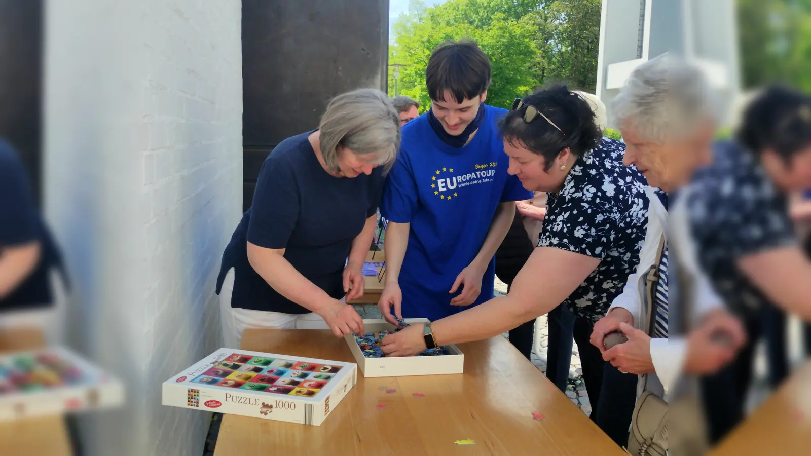 Pfarrgemeinderatsvorsitzende Dr. Andrea Hermann (1. v. l.) und Bücherei-Ehrenamtlicher Jakob Sunderer (2. v l.) legen die ersten Puzzleteile und eröffnen damit die neue Puzzle-Aktion in der Bücherei St. Martin in Germering. (Foto: St. Martin)