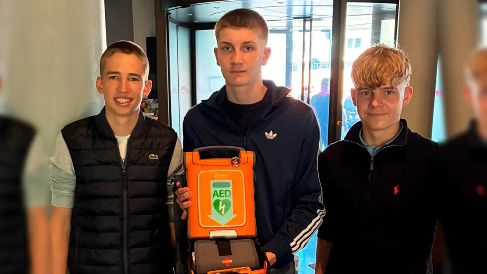 Echte Retter: Drei Jugendliche reanimieren einen Mann auf offener Straße und halten im Anschluss stolz ein lebensrettendes Hilfsmittel in die Kamera: den Automatisierten externen Defibrillator. (Foto: Feuerwehr München)