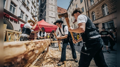 Mitarbeiter einer Zimmerei behauen Eichenbalken beim Bennofest. Aus ihnen entsteht ein Arma-Kreuz für die Kirche St. Barbara in Schwabing-West.  (Foto: Frank Zimmerei und Holzbau )