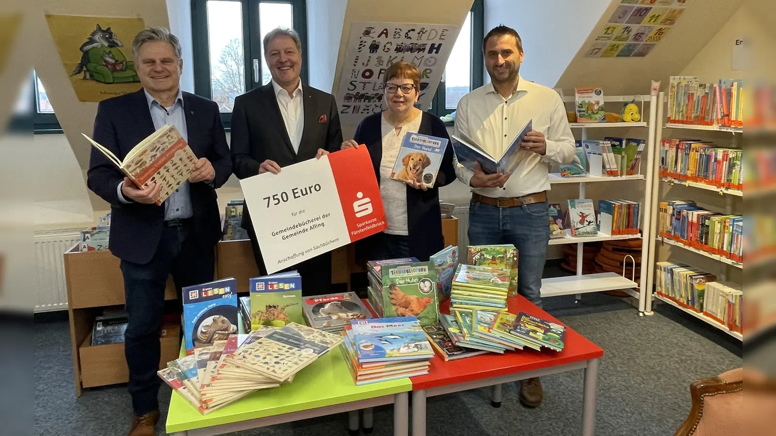 Frank Opitz (Sparkasse Fürstenfeldbruck, 2.v.l.) überbrachte den symbolischen Spendenscheck an Andrea Schlick (Büchereileiterin). Gemeinsam mit Bürgermeister Stefan Joachimsthaler (l.) und Amtsleiter Benedikt Friedinger wurden die neuen Bücherschätze begutachtet. (Foto: Gemeinde Alling)