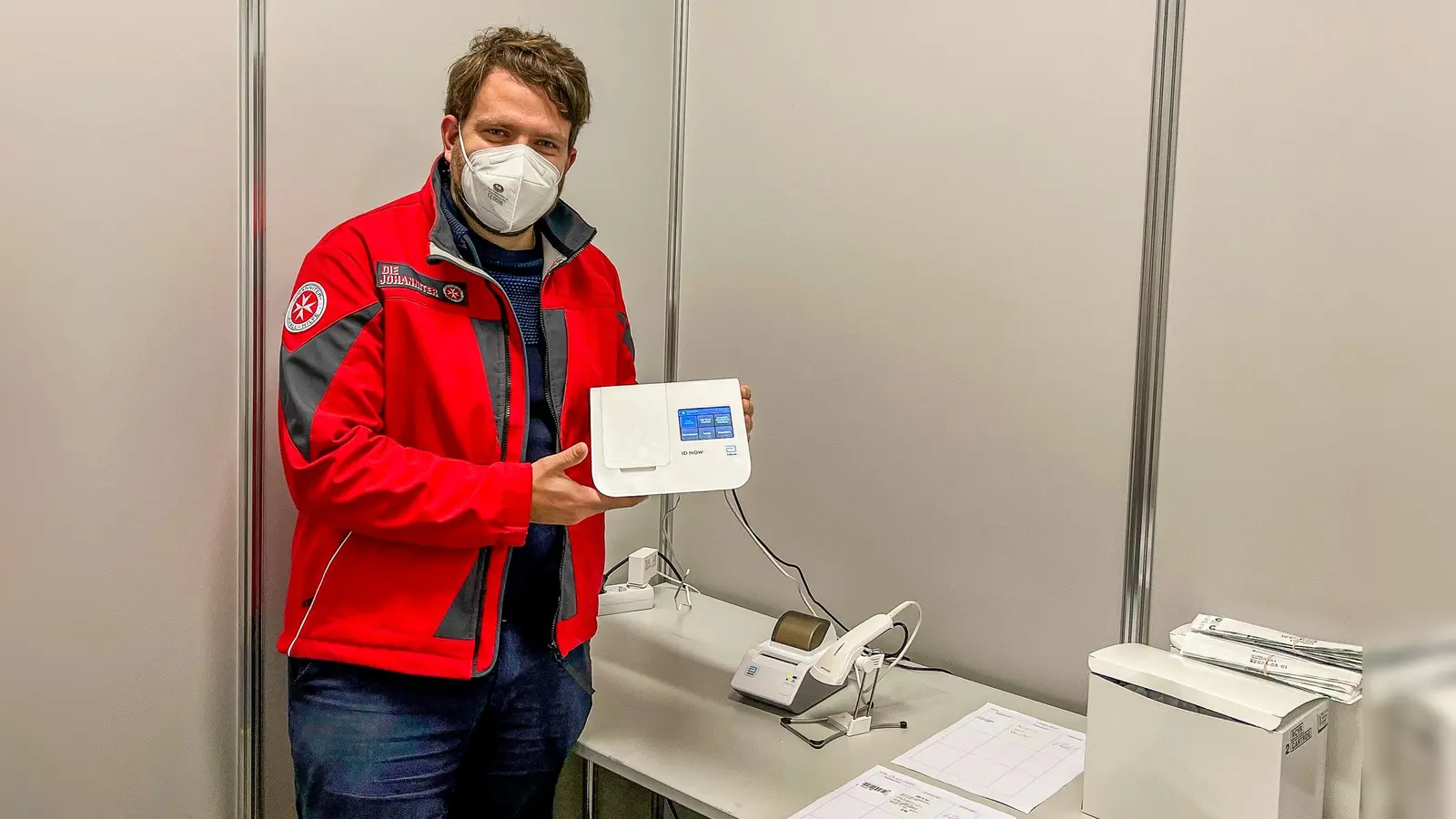 Florian Weber zeigt eines der neuen molekulardiagnostischen Testsysteme für die Testauswertung. (Foto: Johanniter/Jason Podt)