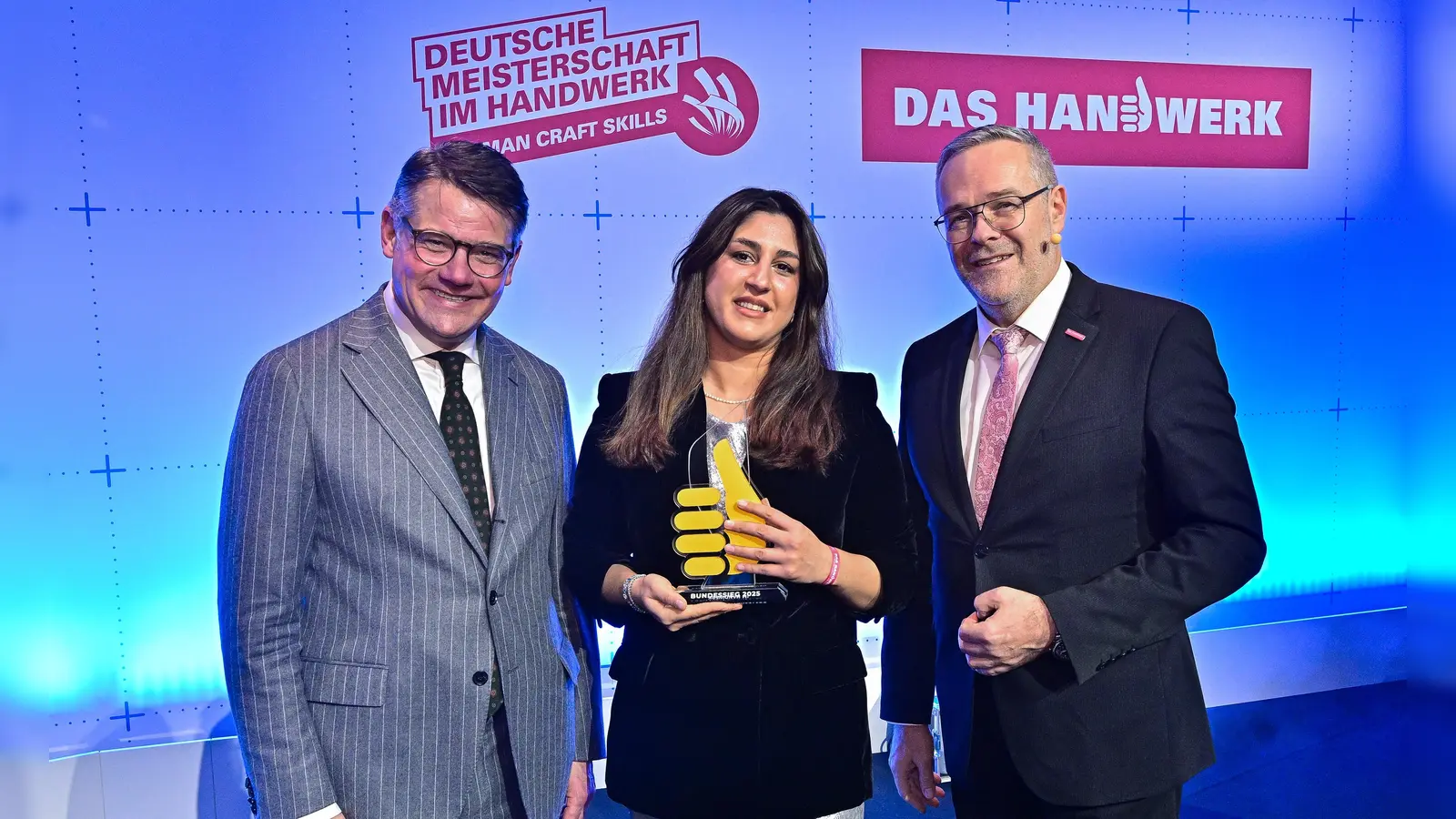 ZDH-Präsident Jörg Dittrich (rechts) und der hessische Ministerpräsident Boris Rhein zeichneten Shoista Ismatuloeva, Fachverkäuferin im Lebensmittelhandwerk, aus. (Foto: ZDH/Martin Joppen & Peter Lorenz)