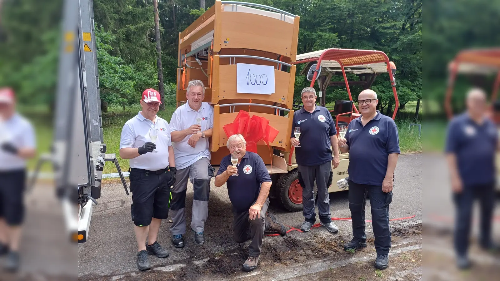 Anton Gutmann, Hans Neugschwendner vom BRK-Kreisverband Neuburg-Schrobenhausen, Hans Ramsteiner, Jörg Zimmermann und Andreas Millik vom BRK-Kreisverband Dachau stoßen auf das tausendste gespendete und in die Ukraine transportierte Bett an. (Foto: BRK)